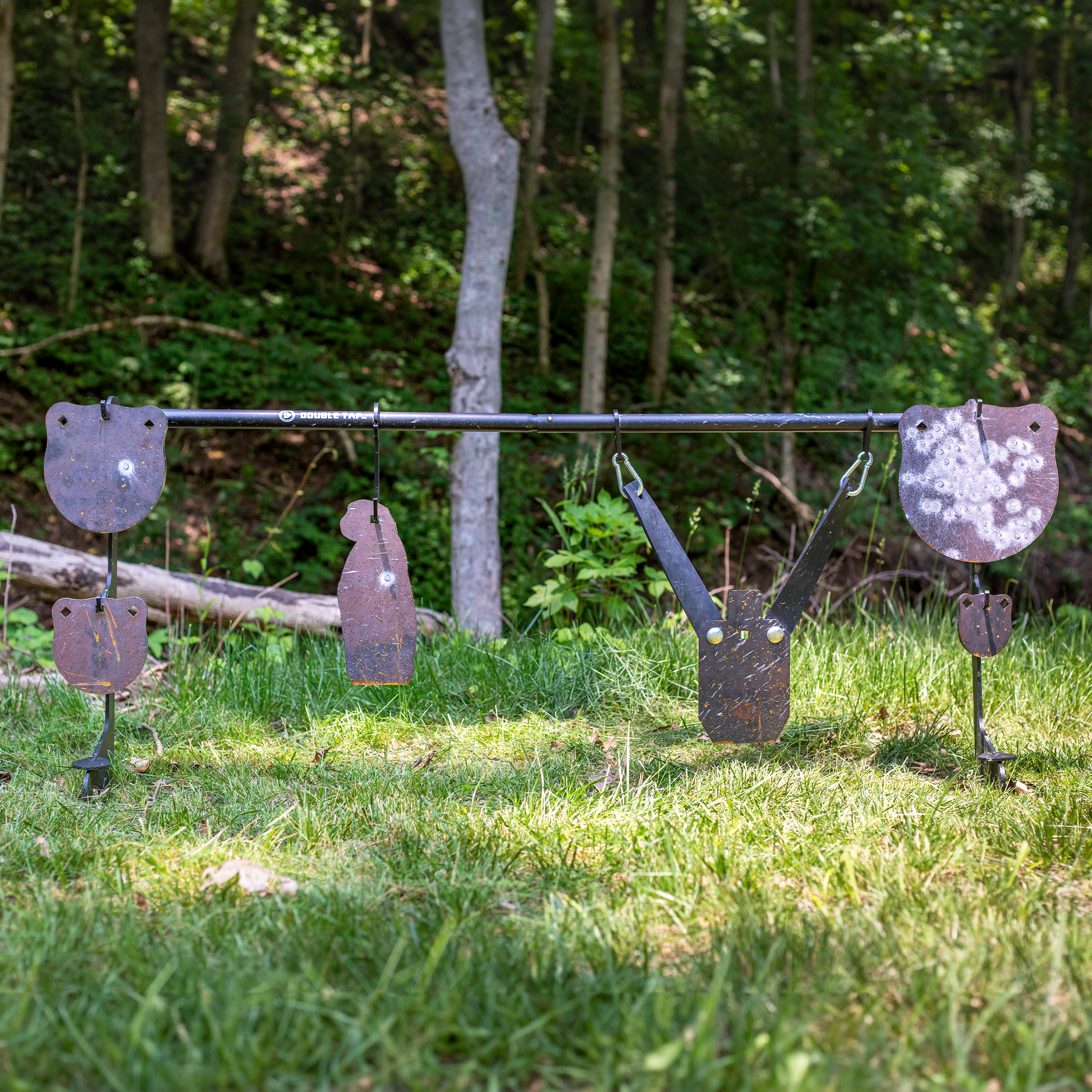Variety of raw steel gong rated for rimfire on a stand with  wooded background