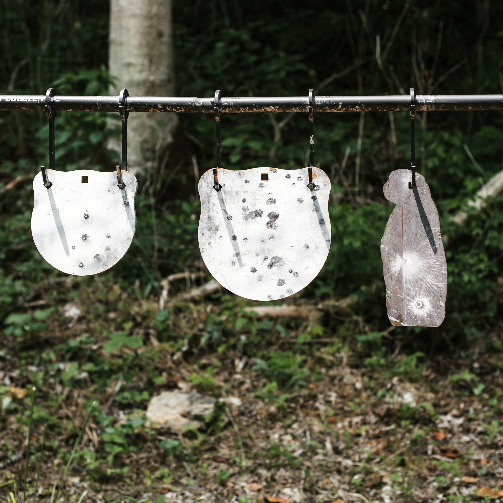 two gongs and a prairie dog steel targets haning off of j-hook hangers from a conduit stand alterntive
