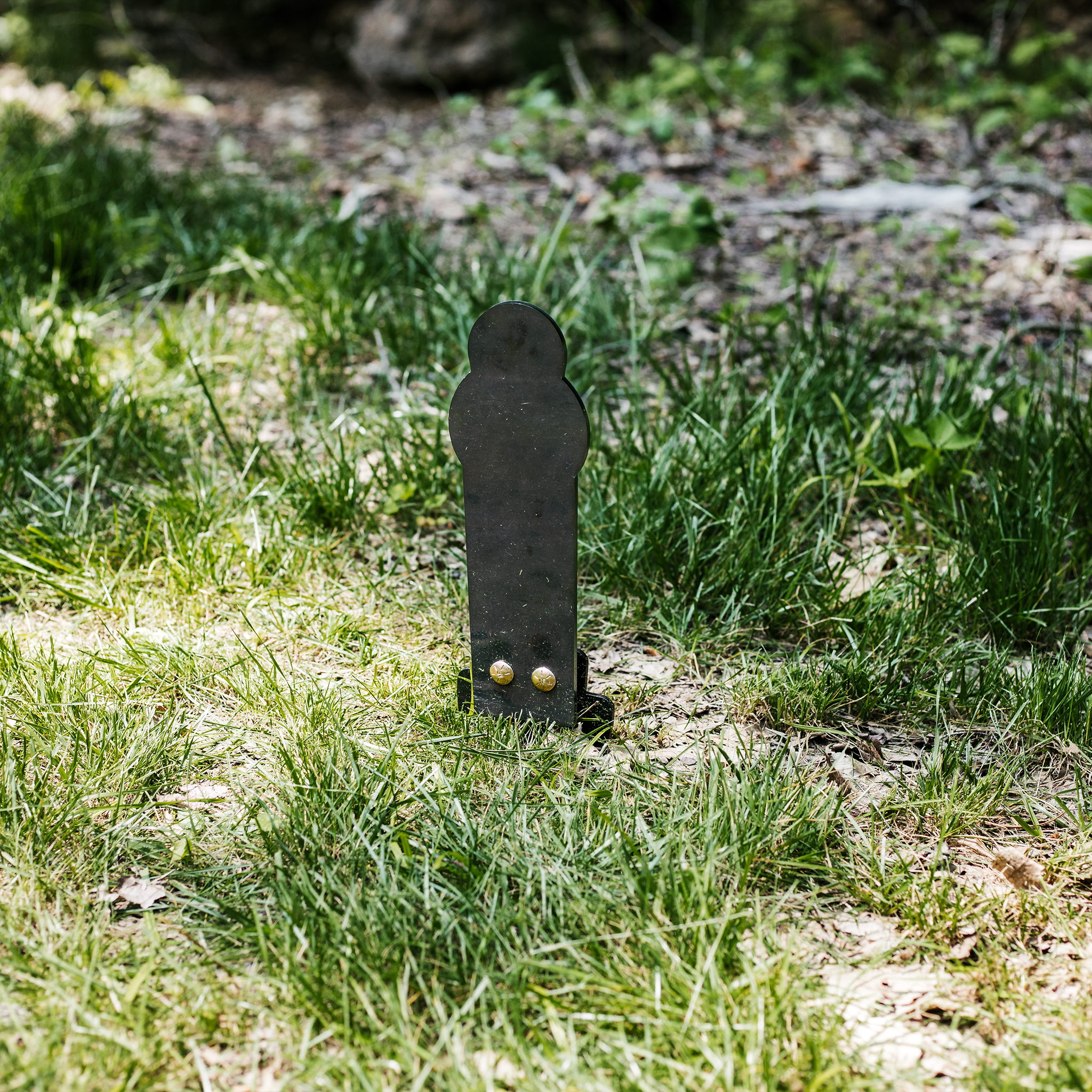 Assembled raw 12" steel rimfire popper ground stake target stomped into the ground