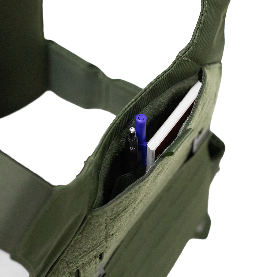Green tactical vest with a admin pocket containing pens and a notebook featuring velcro closure on a white background
