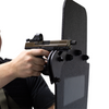 Hand holding a handgun against a black protective shield using the bolt on gun support bracket on a white background
