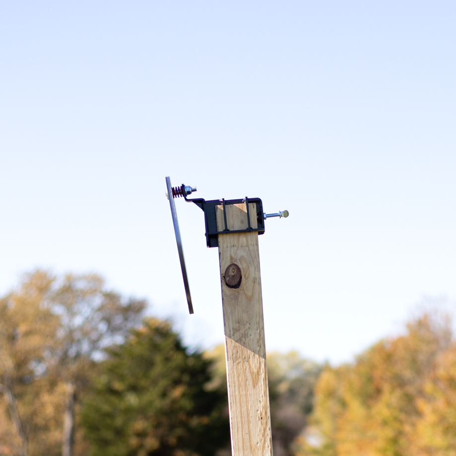 up close view of 2x4 target hanger for safely hanging ar500 steel targets from a 2x4 with a 2x4 stand and base with spiked feet at an outdoor range