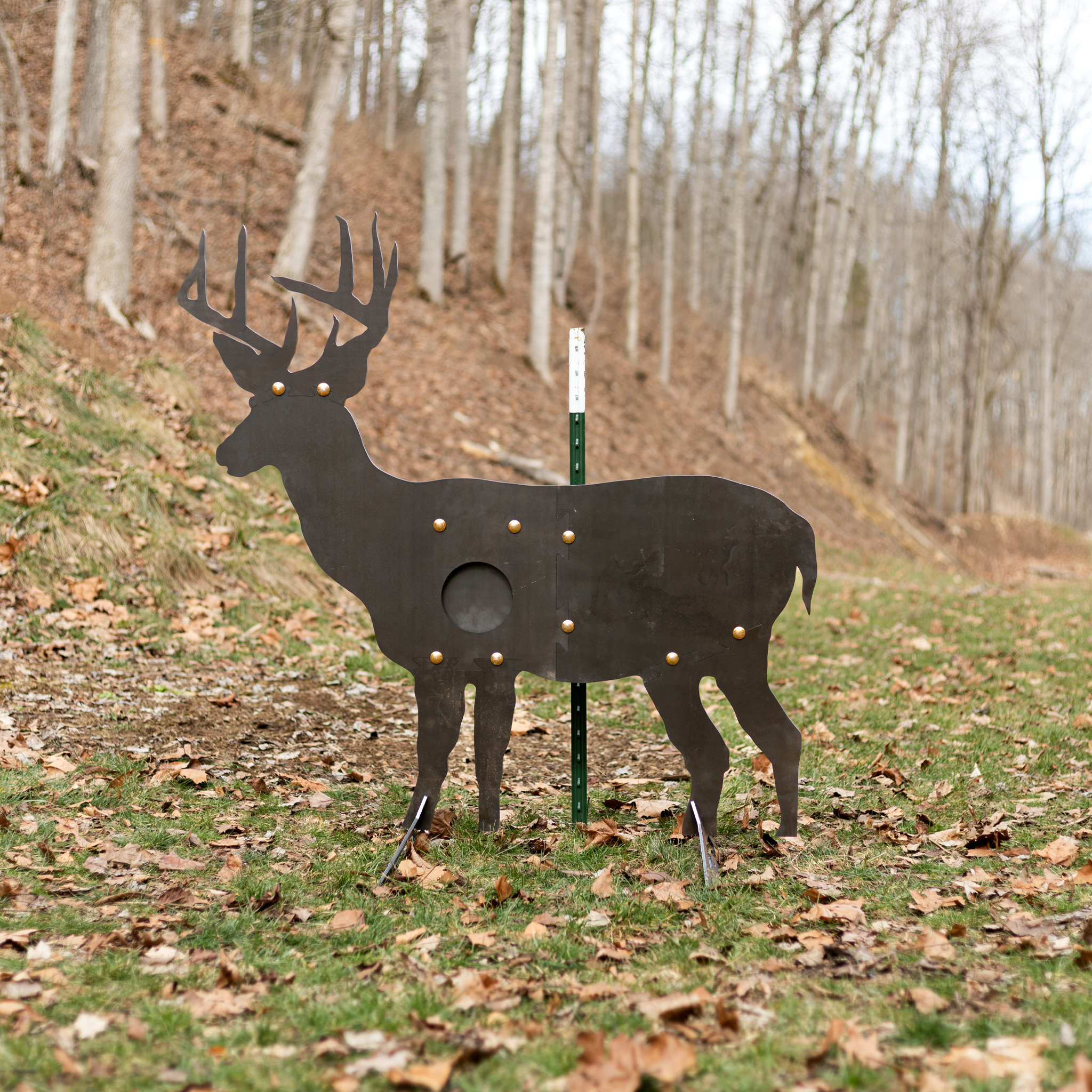 Unpainted deer-shaped sr500 steel target with reactive vital swinging paddle standing in a wooded outdoor target range