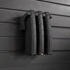 Three black AR-15 magazines stacked on mag slat wall hanger, installed on an Assault Wall tactical slat wall