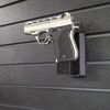 Assault Wall magazine mounted hanger for .22LR single stack pistols, Left facing mount with gun hanging from mag well on a black Assault Wall slat wall panel