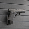 Right facing black plastic magazine mounted 9mm pistol hanger installed on Assault Wall Tactical slat wall