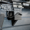 Close-up of an AR-15 rifle mounted by its magazine well on an Assault wall caliber specific gun mount installed on a slat wall
