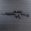 Left facing AR-15 rifle mounted by its magazine well on a black Assault wall slat wall panel