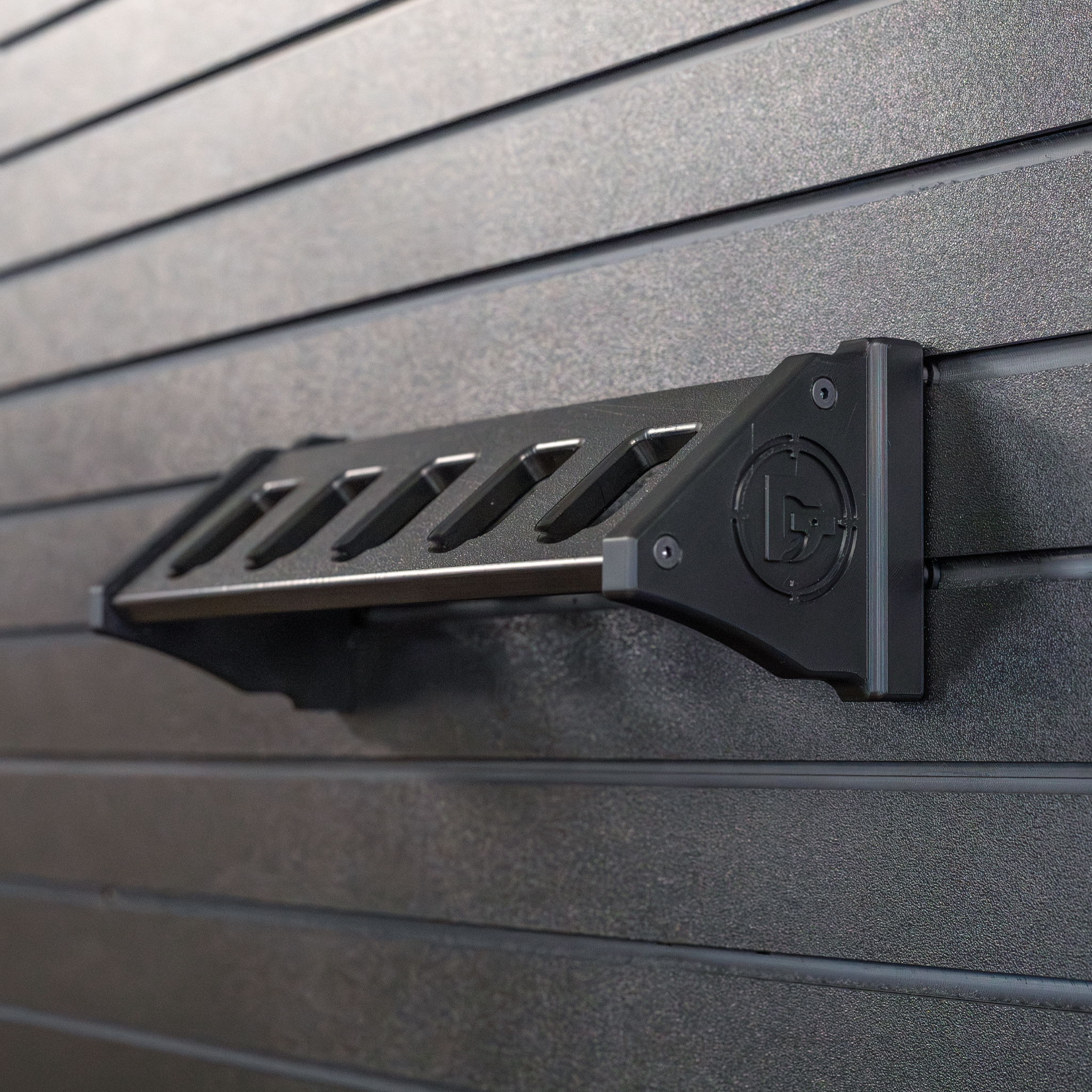 Black plastic five pistol storage and organization mountthat is installed on a black Assault Wall panel for tactical guns