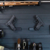 Left & Right facing black plastic caliber specific  mag mounted pistol hangers installed on Assault Wall Tactical slat wall showcasing the adjustable mounting angles and directional mounts. 