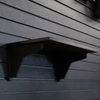 15" black plastic shelf with two support backets mounted on a black tactical slat wall