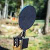 8" AR500 fall over gong sitting upright on 2x4 stand on a natural background