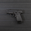 Left facing black plastic magazine mounted 9mm single stack pistol hanger installed on Assault Wall Tactical slat wall