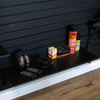 Black 30" organizational storage shelf with various items including pistol magazines, earmuffs, ammo boxes, and cleaning products against a dark Assault wall for storing tactical gear.