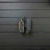 Assault Wall Magnetic tactical gear mount shown with pistol magazine and tactical multi-tool mounted vertically by the mount's built in magnets, mount has been slid into position on a black Assault Wall slat panel
