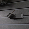 Black plastic barrel mounted pistol hanger that has a carbon fiber rod, shown mounted to our Assault Wall tactical slat wall panel