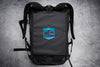 Lifestyle image of caliberx-iiia soft body armor rectangle laying on top of compatible backpack on a grey background