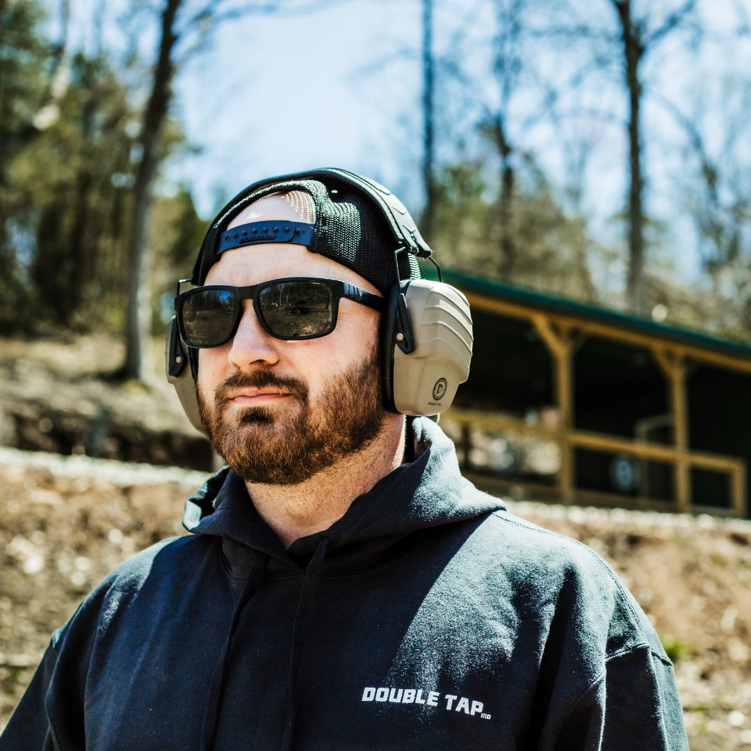 Male model wearing double tap industries passive earmuffs for ultimate hearing protection at the shooting range