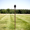 Steel target mounted on adjustable T-post hanger at outdoor shooting range