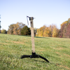 Round steel target mounted on adjustable 2x4 target stand with spiked feet on grassy slope to demonstrate adjustability 