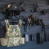 Tactical gear including a helmet, vest, magazines, and weapons mounted on the Assault Wall tactical slat wall panel wall system.