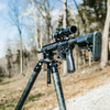 rifle mounted on panoramic leveling head on carbon fiber shooting tripod at an outdoor range