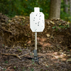Steel target mounted painted white on adjustable 2x4 shooting stand at outdoor range