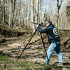 shooter at range lining up a shot with rifle mounted on carbon fiber shooting tripod
