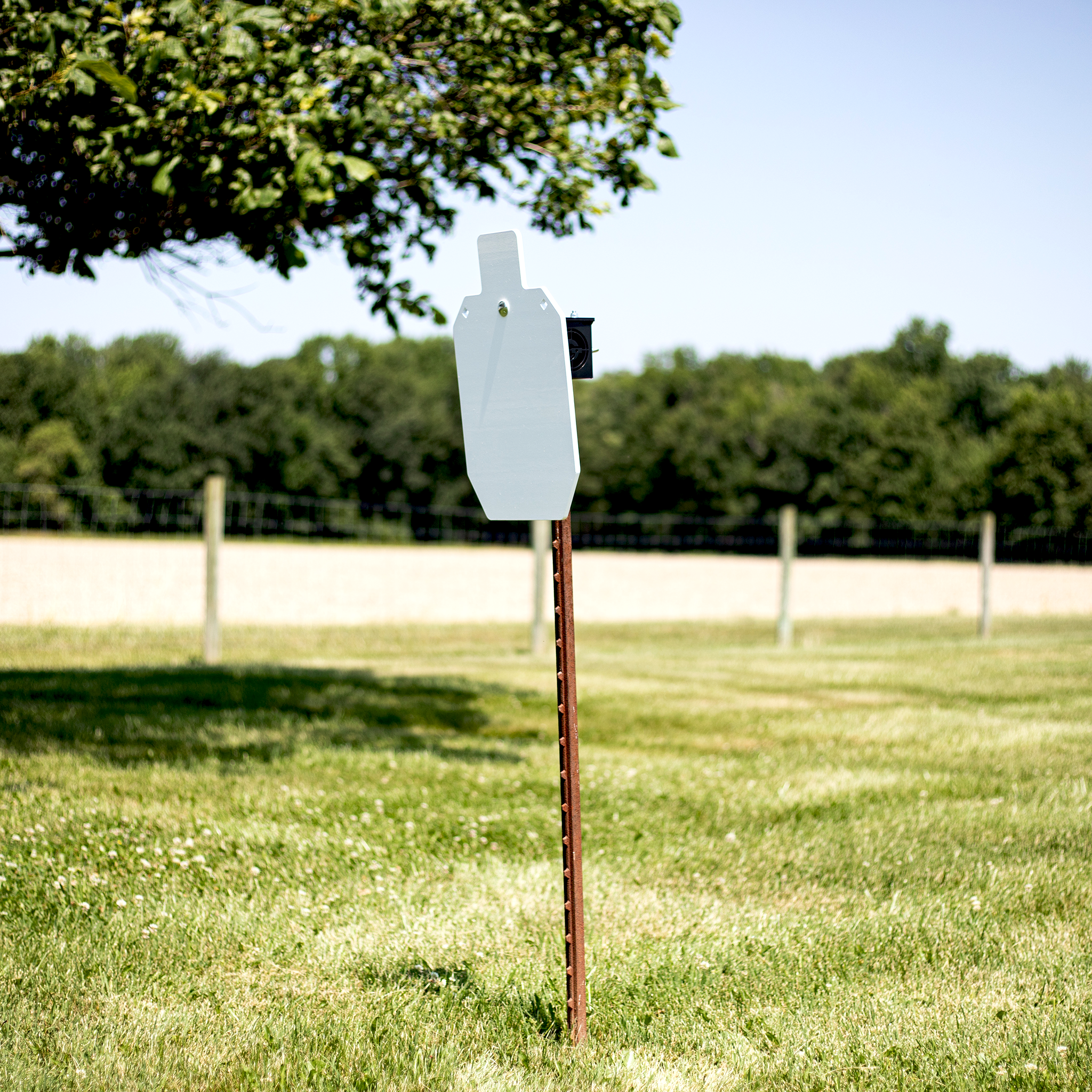 Steel target mounted on adjustable T-post hanger at outdoor shooting range