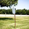 Steel target mounted on adjustable T-post hanger at outdoor shooting range